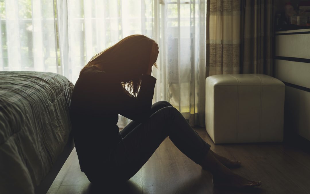 depressed woman sitting in the dark bedroom