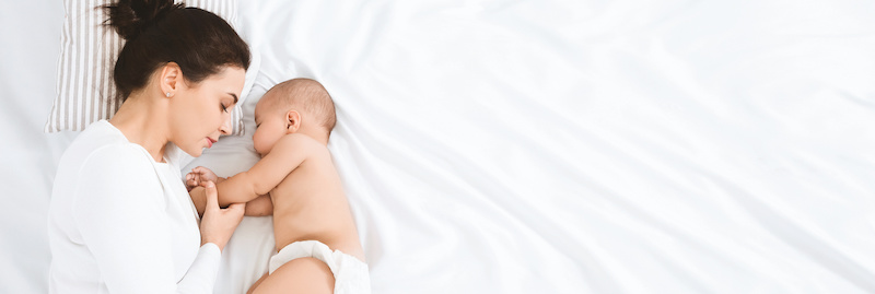 Maternity love. Young mom sleeping with her baby, panorama with empty space, top view