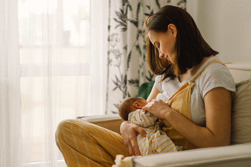 Newborn baby boy sucking milk from mothers breast. Portrait of mom and breastfeeding baby.